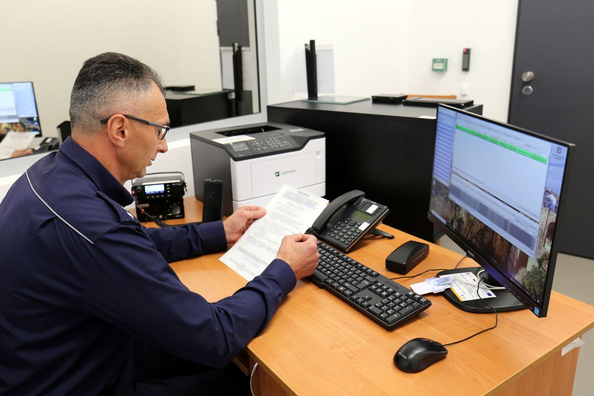 umundurowany policjant siedzi przy biurku przed komputerem 