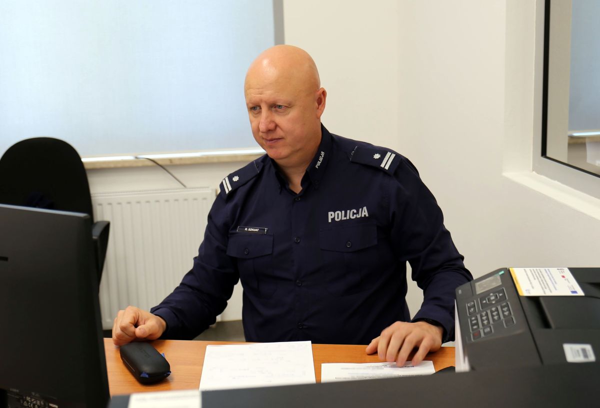 umundurowany policjant siedzi przy biurku przed komputerem 