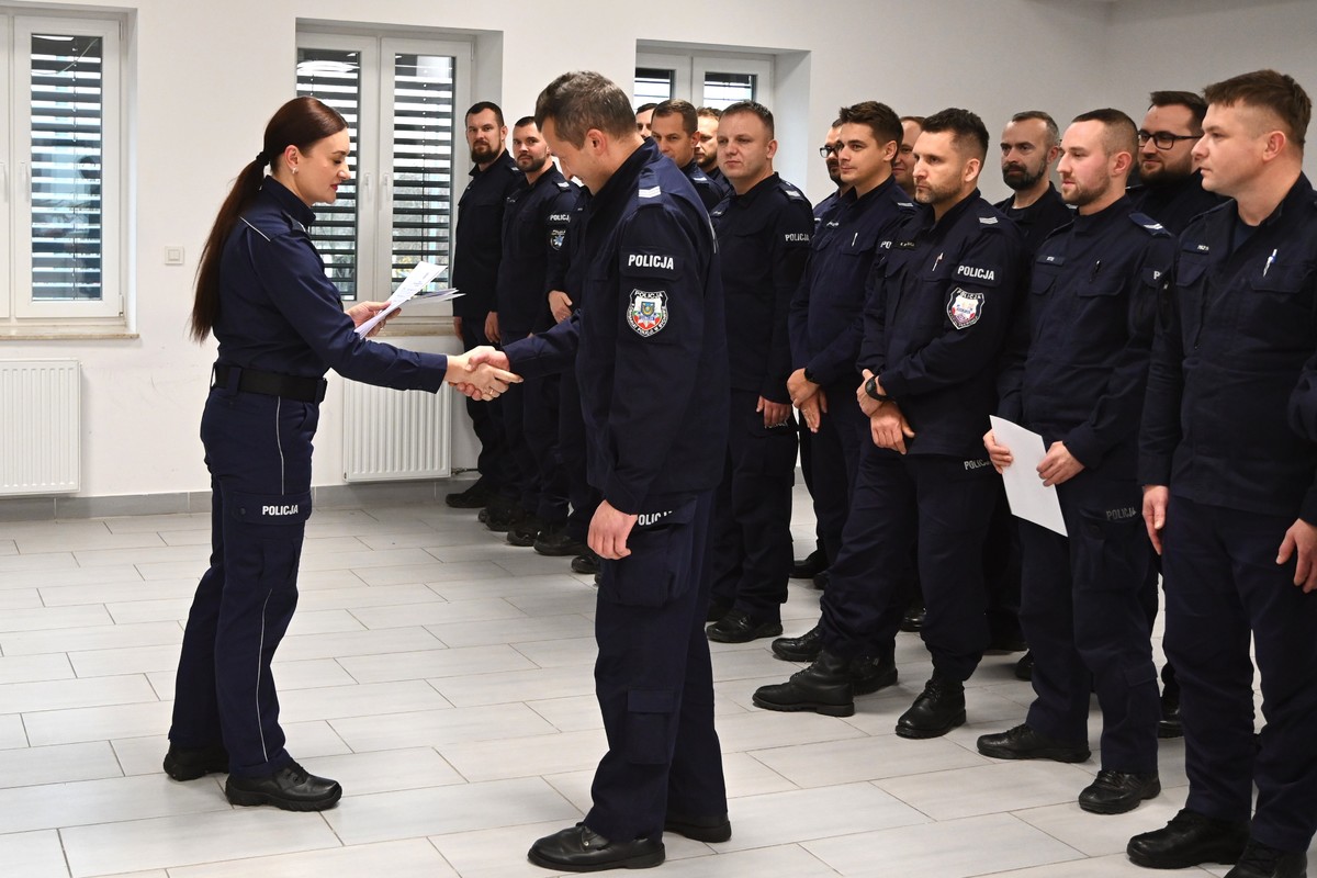 policjantka podaje rękę i wręcza dyplom absolwentowi sszkolenia. W tle znajdują sie policjanci, którzy uczestniczyli w szkoleniu