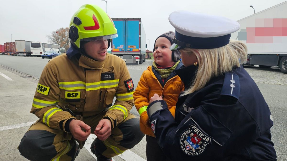 strażak i policjantka rozmawiają z dzieckiem 