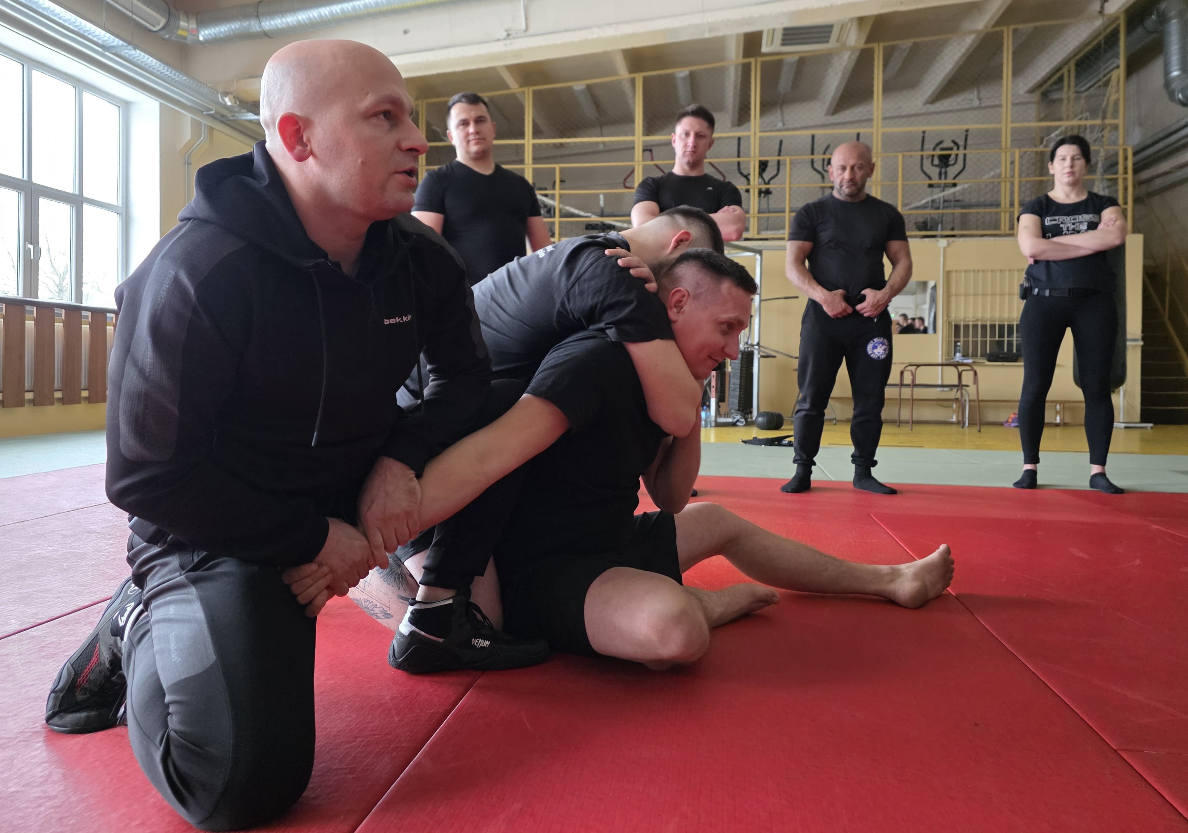 na sali gimnastycznej instruktor pokazuje sposób obezwłanienia osóby