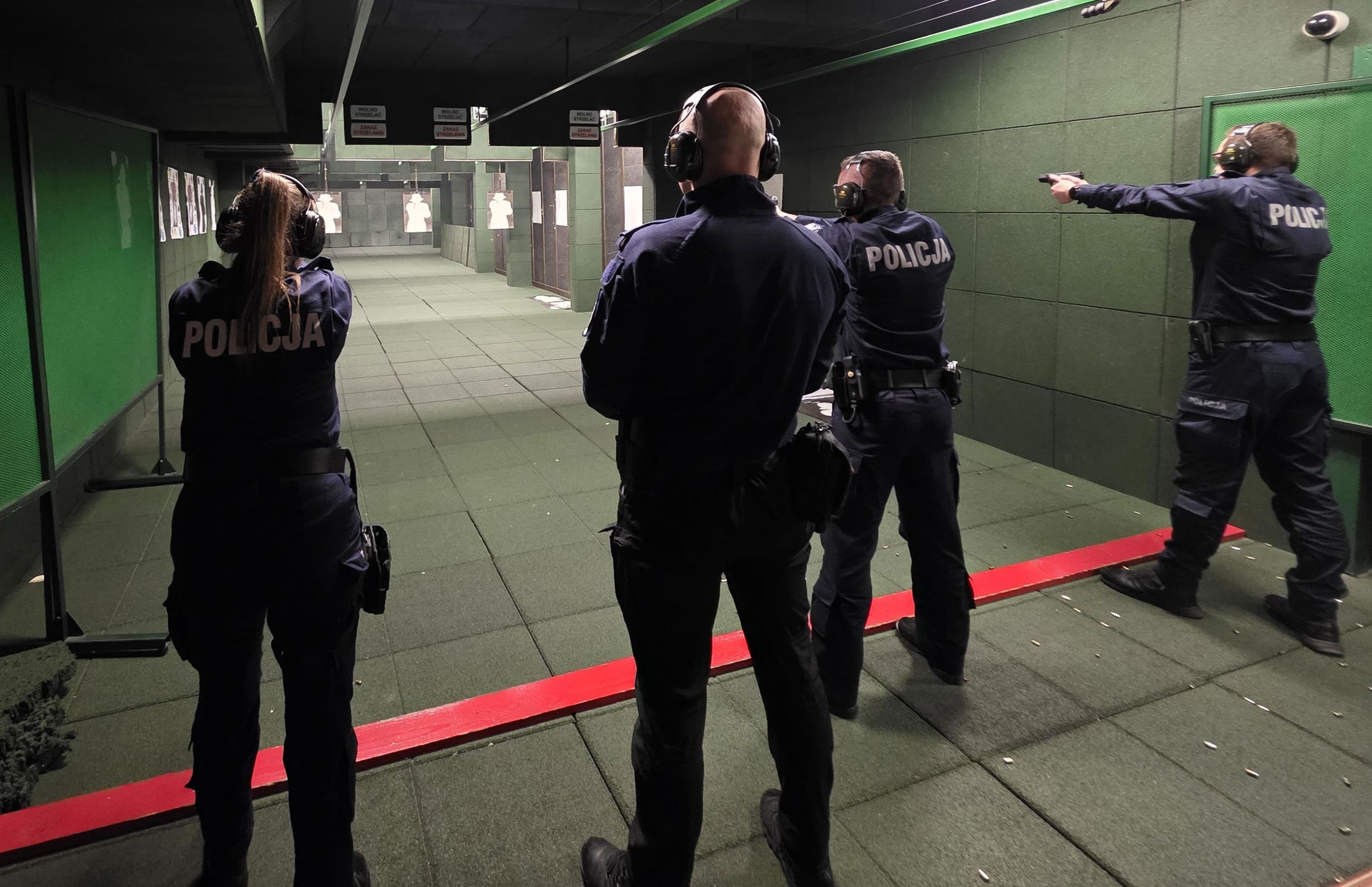 umundurowani policjanci na strzelnicy trzymają broń skierowaną w kierunku kulochwytu