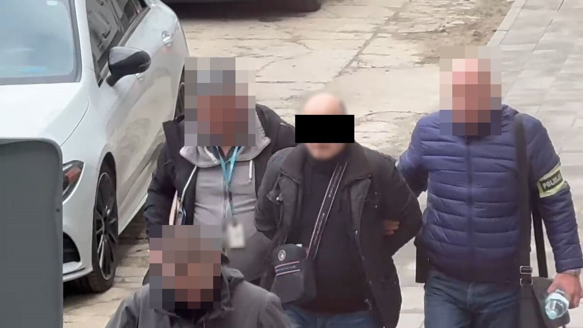 Policjanci prowadzą zatrzymanego mężczynę.