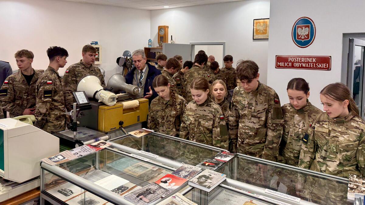 uczniowie oddziału mundurowego stoją przy gablotach z eksponatami w Policyjnej Izbie Pamięci