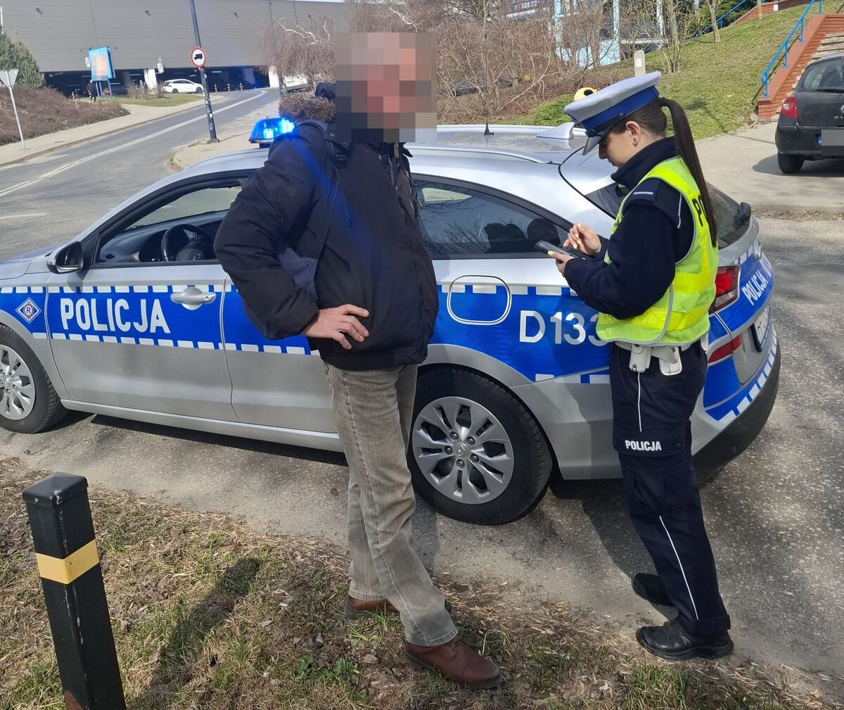 policjantka podczas kontroli drogowej z pieszym, w tle widać radiowóz