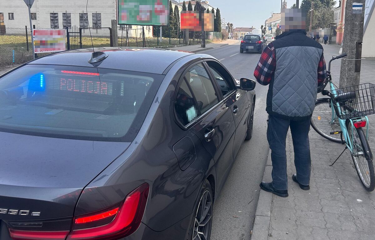 policjanci podczas kontroli drogowej z pieszym, w tle widać radiowóz