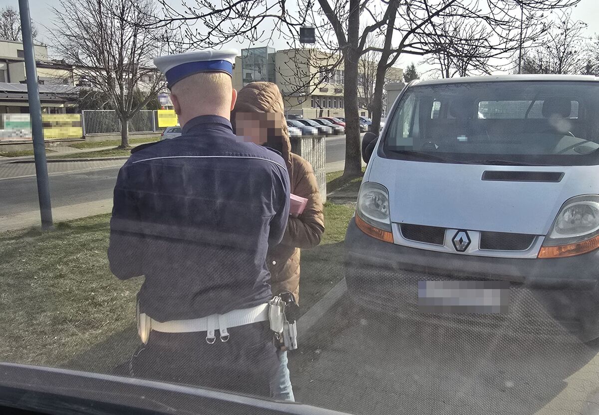 policjant podczas kontroli drogowej z pieszym, w tle widać samochód