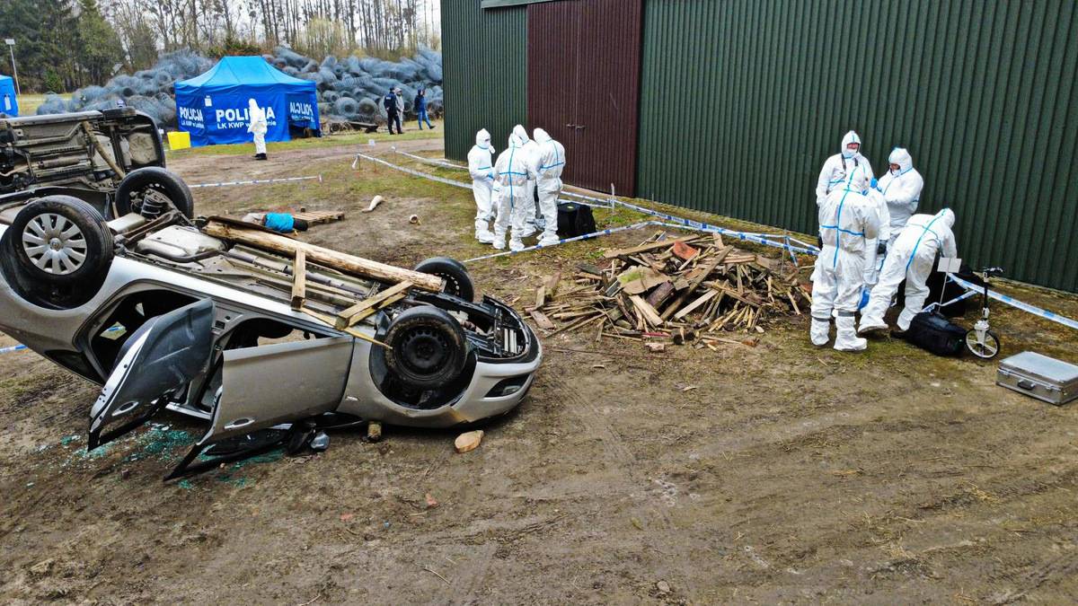 Policjanci ubrani w stroje ochronne zabezpieczają ślady na miejscu wypadku.