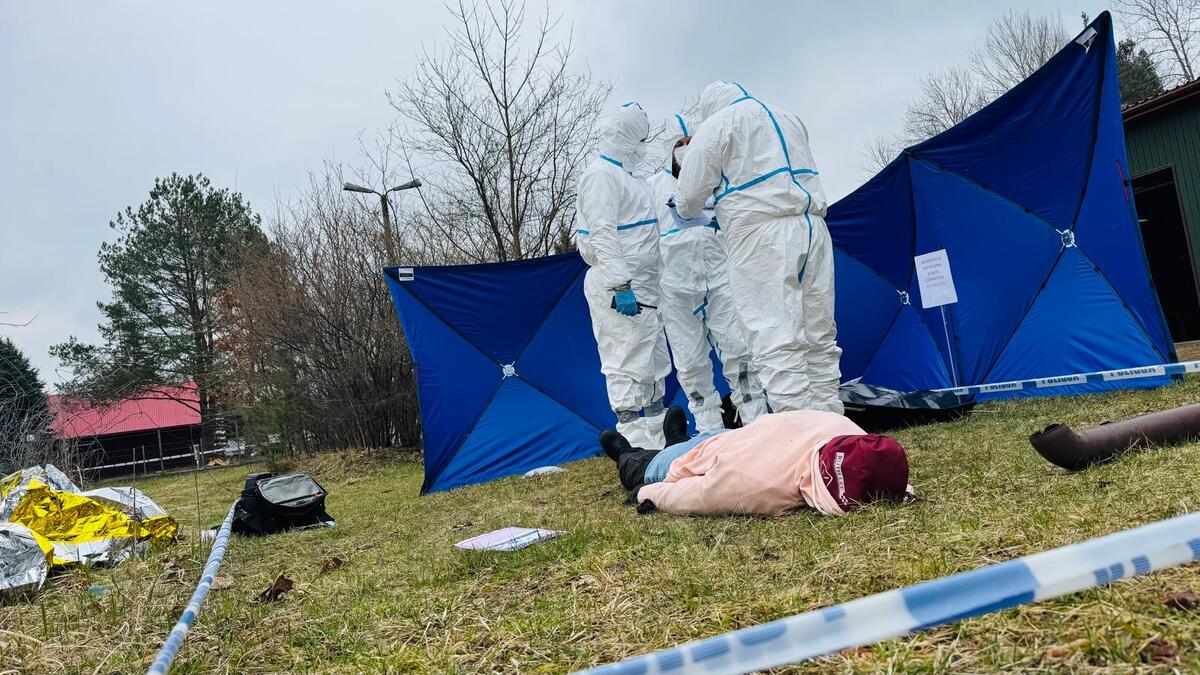 Policjanci ubrani w stroje ochronne zabezpieczają ślady na miejscu wypadku.