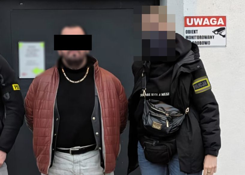 Policjanci prowadzą zatrzymanego mężczyznę.