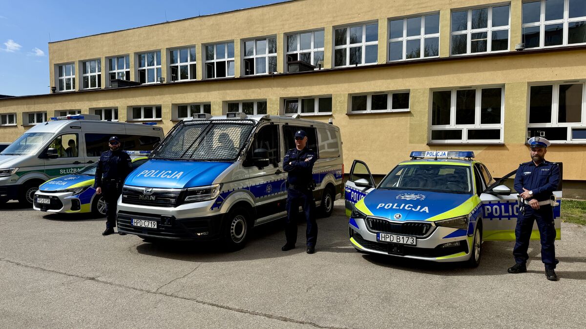 policjanci stoją przy oznakowanych radiowozach 