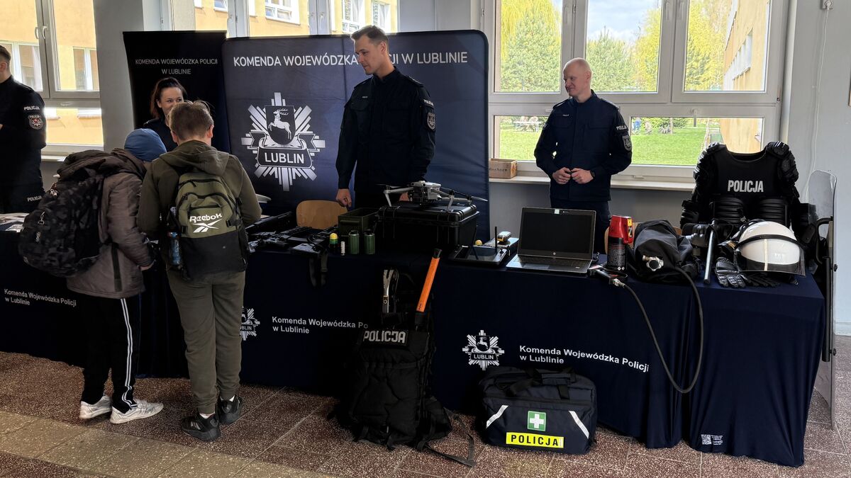 policjanci przy stoisku promującym policję rozmawiają z uczniami