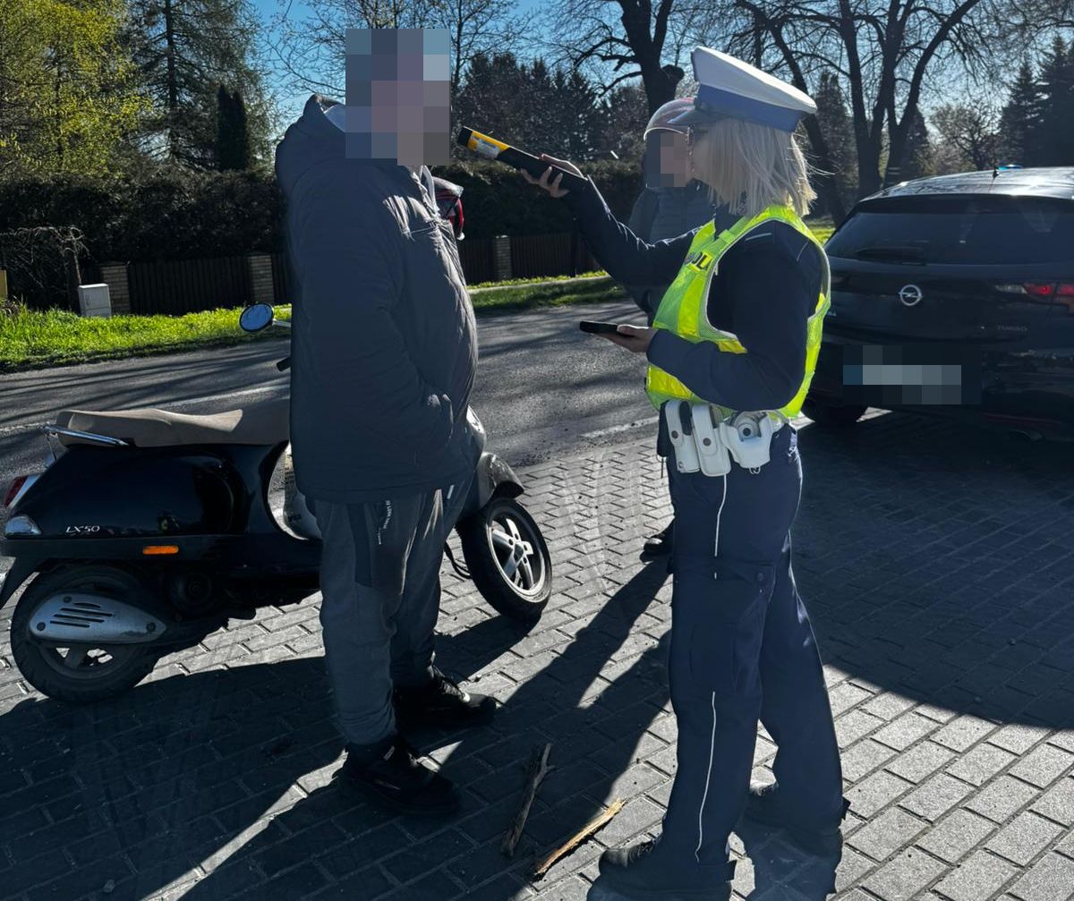 policjantka podczas kontroli drogowej sprawdza trzeźwość kierującego jednośladem
