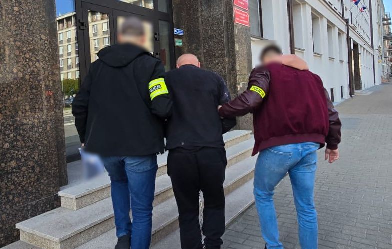 Policjanci wchodzą z zatrzymanym do prokuratury.