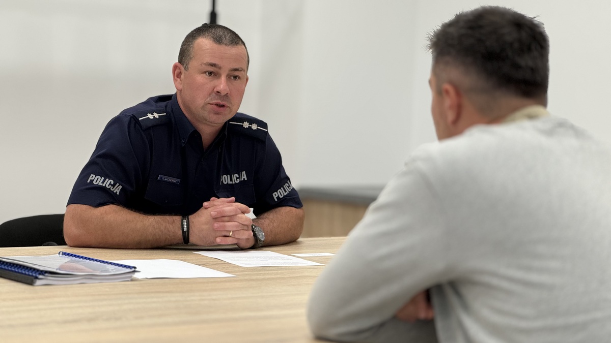 Policjant rozmawia z pozorantem na symulowanym spotkaniu z mieszkańcem.