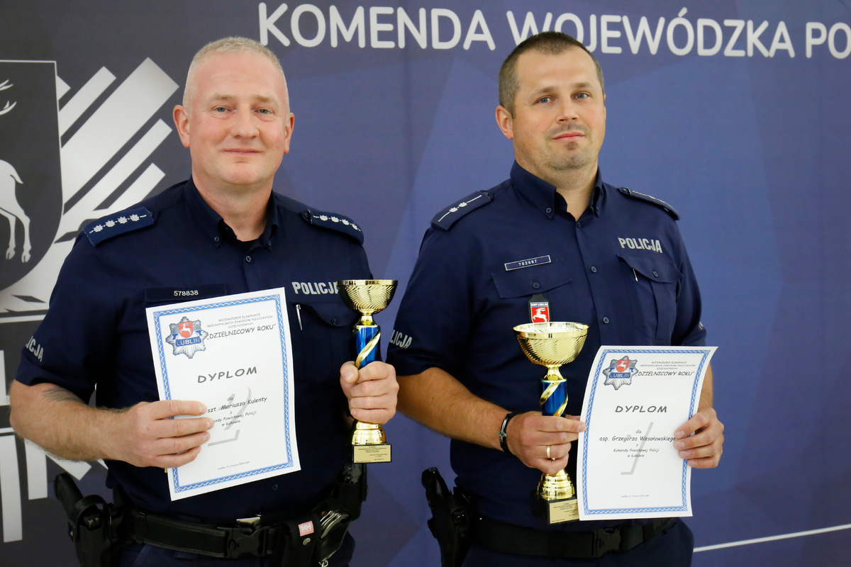 Dwóch policjantów, którzy zajęli pierwsze i drugie jmiejsce w konkursie pozują do zdjęcia z pucharami i dyplomami