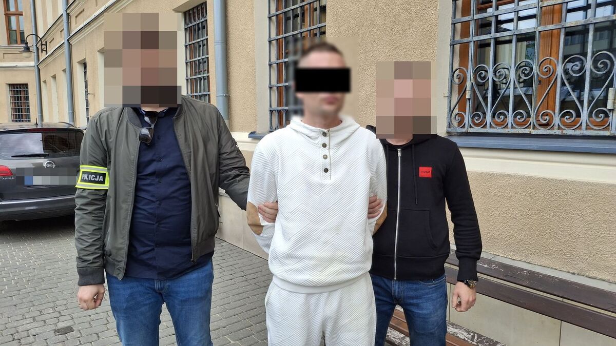 Policjanci prowadzą zatrzymanego mężczyznę.