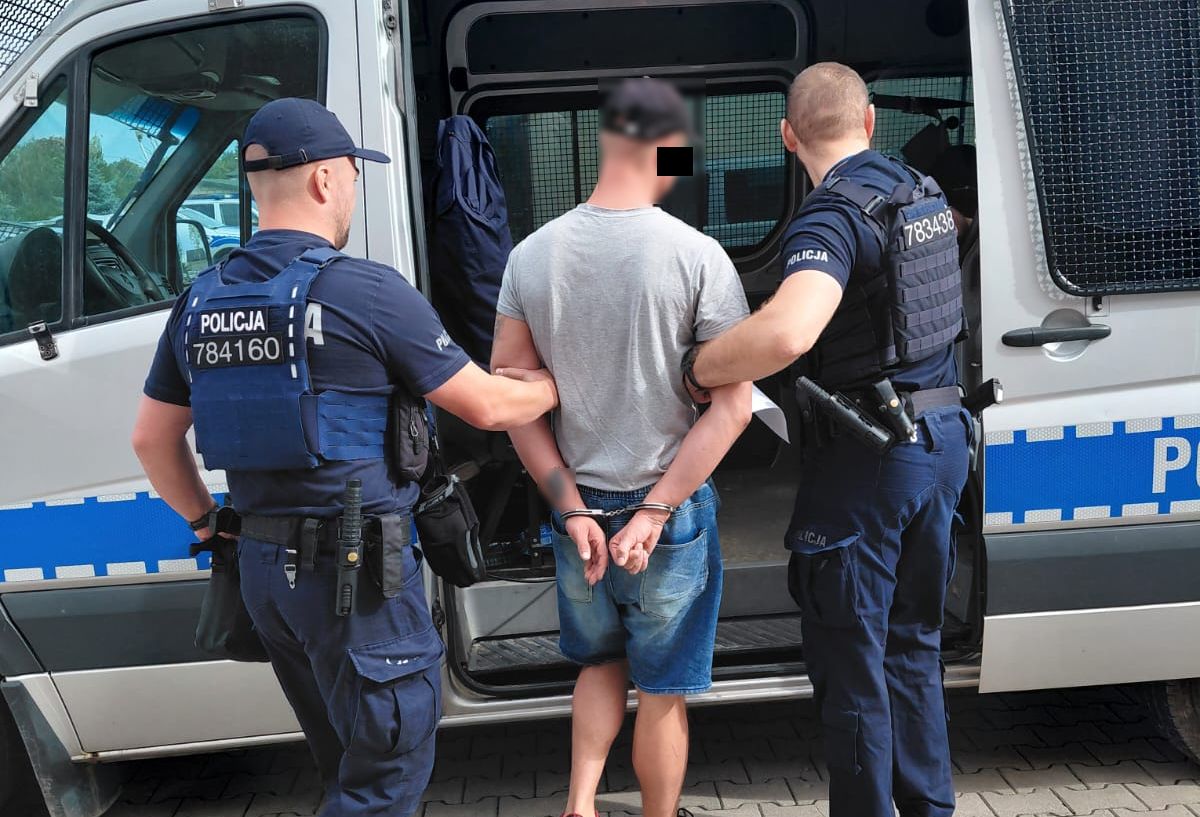 Policjanci prowadzą zatrzymanego mężczyznę.