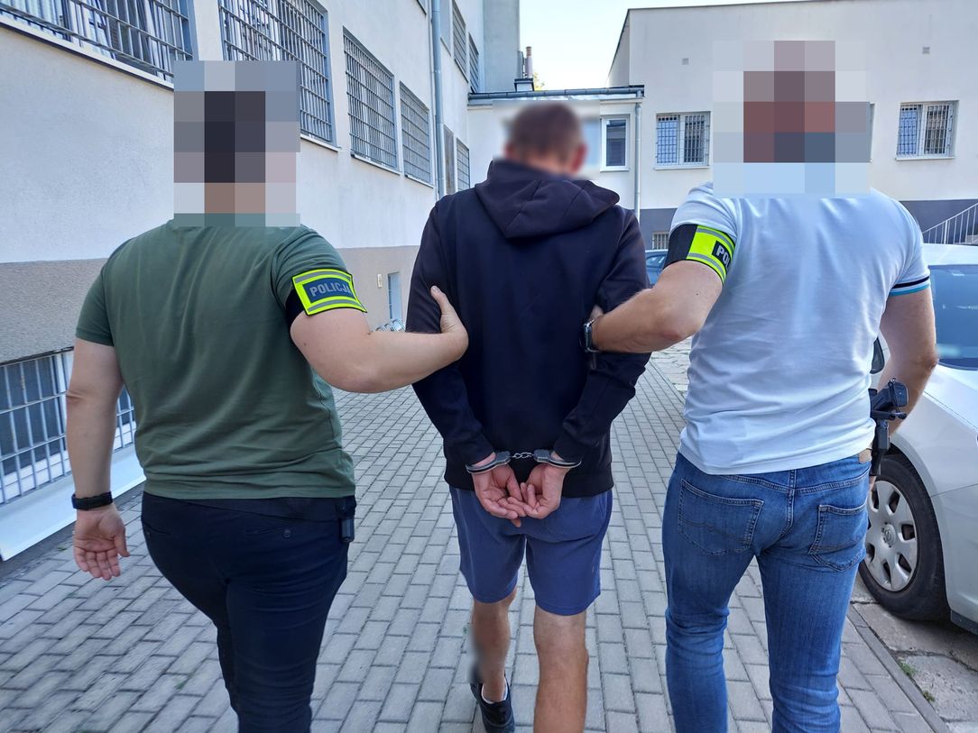 Policjanci prowadzą zatrzymanego mężczyznę.