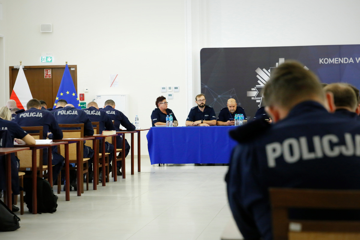 Policjanci rozwiązuja testy z wiedzy. W drugim planie komisja sędziowska złożona z funkcjonariuszy KWP w Lublinie