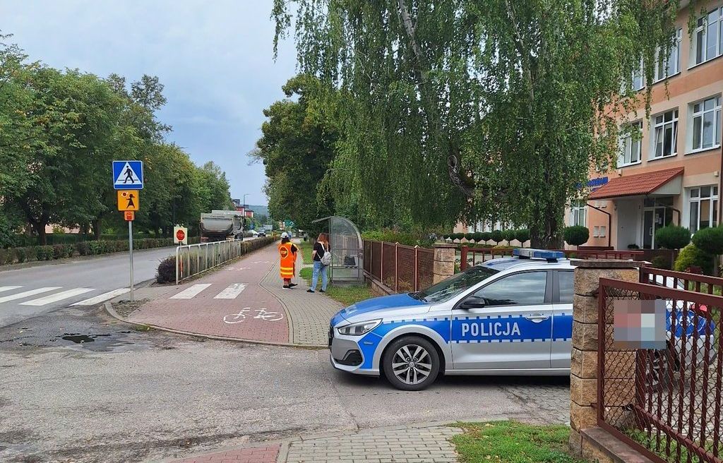 oznakowany radiowóz policyjny przy budynku szkoły 