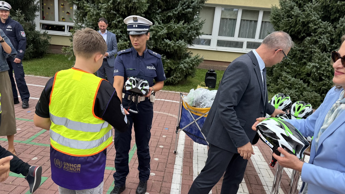 Policjantka daje kask dziecku.