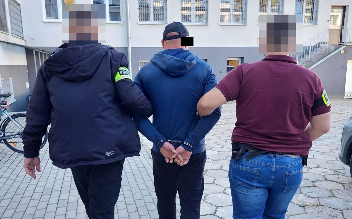 Policjanci prowadzą zatrzymanego mężczyznę.