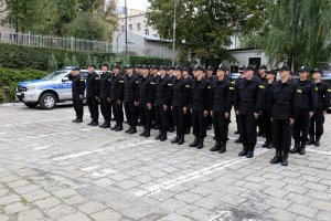 Plac przed Komendą Wojewódzka Policji w Lublinie. Nowi funkcjonariusze ubrani w czarne moro stoją na baczność.