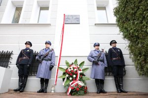 Czterech policjantów stoi na baczność po dwóch stronach tablicy umieszczonej na ścianie Komendy Wojewódzkiej Policji w Lublinie. Dwóch Policjantów jest ubranych w mundury współczesne a dwóch w mundury policji państwowej.