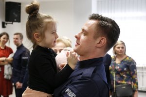 Policjant trzyma na rękach dziewczynkę.