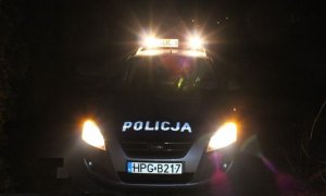 policyjny radiowóz nocą z włączonymi światłami
