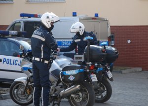 policjanci  ruchu drogowego  na motocyklach, w tle oznakowany radiowóz