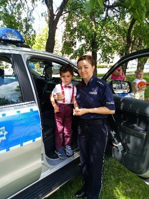 policjantka zapoznaje dzieci z wyposażeniem policyjnym oraz pokazuje policyjny radiowóz