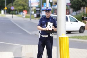 Policjant Ruchu Drogowego trzyma kartę punktacji z cyfrą numer 6.