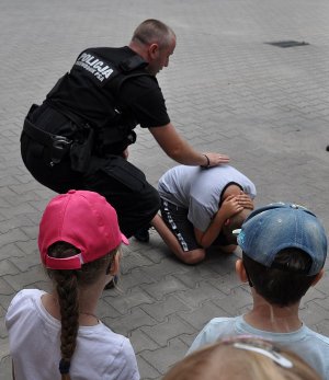 policjant prezentuje dziecku jak bronić się przed atakiem agresywnego psa