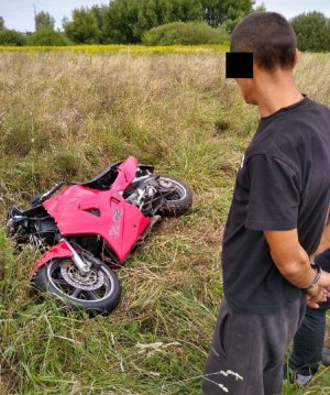 zatrzymany mężczyzna, w tle widać odzyskany skradziony motocykl