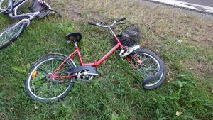 Zdjęcie poglądowe przedstawiające rower koloru czerwonego. Rower ma pogięte przednie koło w wyniku zdarzenia drogowego