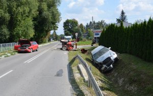 uszkodzone dwa samochody osobowe marki Audi oraz przewrócony ciągnik rolniczy