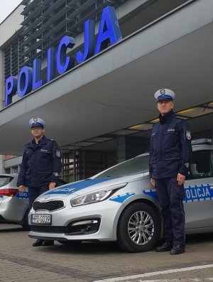 policjanci stojący przed budynkiem KPP w Radzyniu Podlaskim, obok nich zaparkowany jest radiowóz