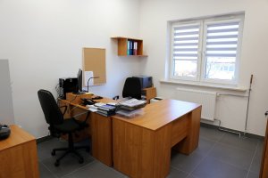 Pomieszczenie służbowe w nowym komisariacie. Wewnątrz znajdują się dwa biurka z komputerem drukarką, dwa krzesła obrotowe czarne.