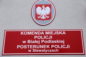 Fragment elewacji nowego budynku na nim umieszczone godło oraz tablica informacyjna z napisem Komenda Miejska Policji w Białej Podlaskiej Posterunek Policji w Sławatyczach.