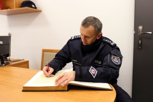 Komendant Wojewódzki Policji wpisuje się do księgi pamiątkowej.