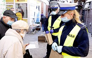 Policjanci Wydziału Ruchu Drogowego rozdają maseczki osobom starszym na jednym z Lubelskich targów.