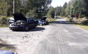 dwa rozbite pojazdy stojące na poboczu drogi