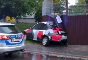 uszkodzony samochód marki Honda stojący przy metalowej wiacie, obok policyjny radiowóz