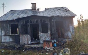 front drewnianego domu, widoczne okopcenia wybite szyby, uszkodzony dach