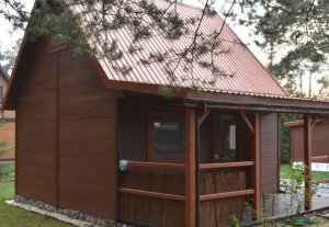 Drewniany, brązowy domek letniskowy usytuowany na działce rekreacyjnej w miejscowości Lejno