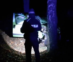 policjant stoi przed rozbitym pojazdem