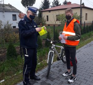 policjant daje rowerzyście odblaskową kamizelkę