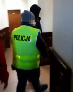 policjant prowadzi zatrzymanego